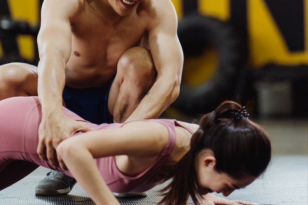 coach helping lady for push up at the gym