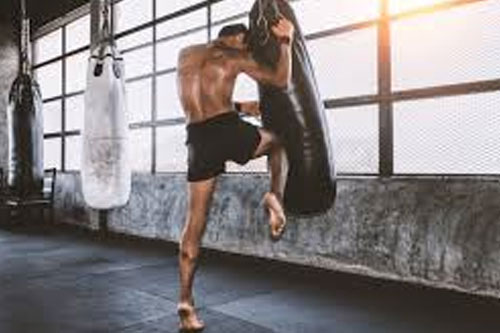 man doing muay by kicking in a punching bag