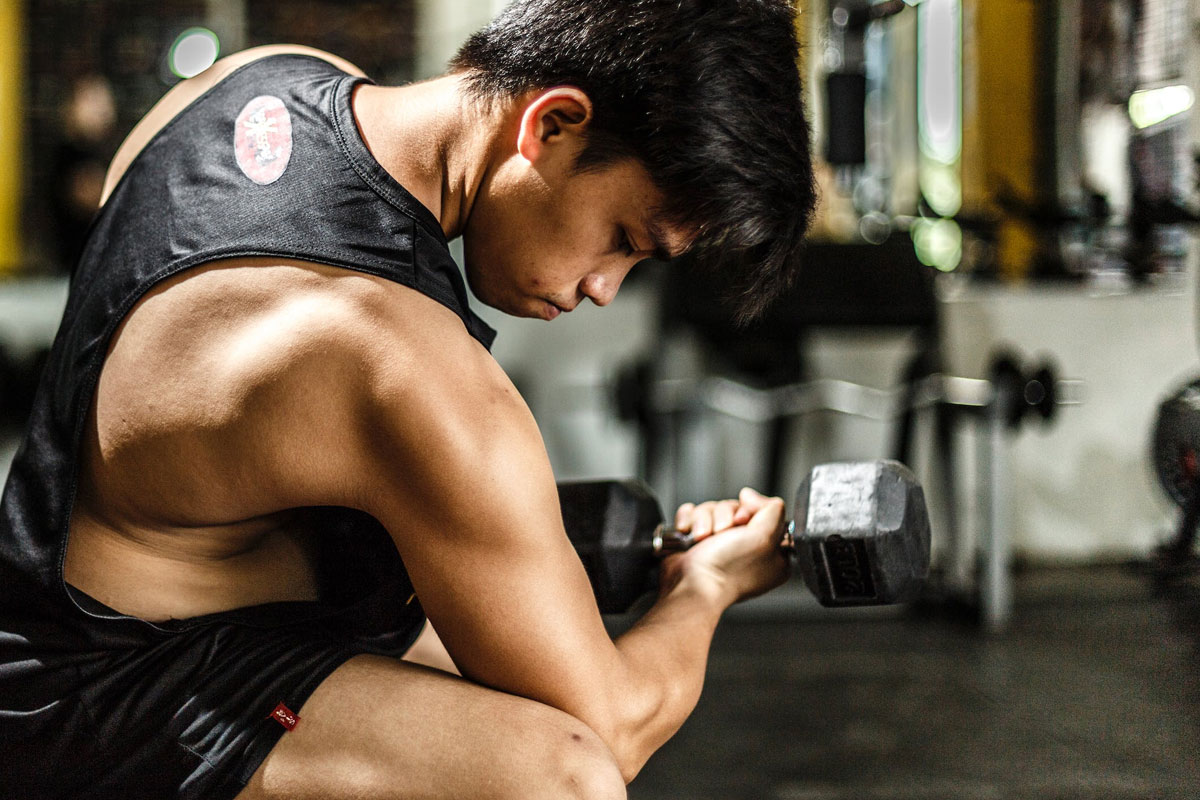 man flexing his biceps while lifting dumbbells