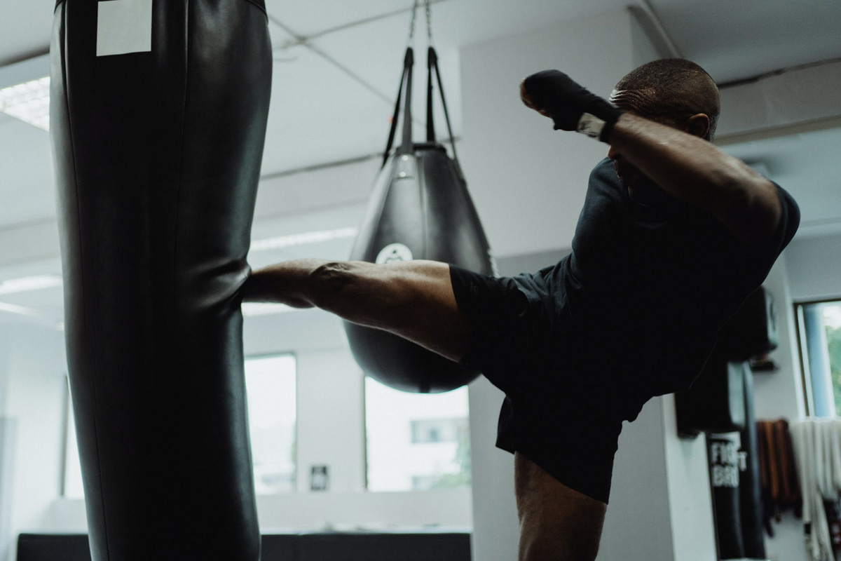 man kicking a boxing bag in gym