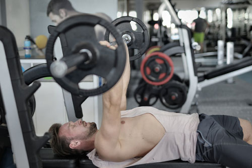 strong sportsman doing bench press during workout in modern gym